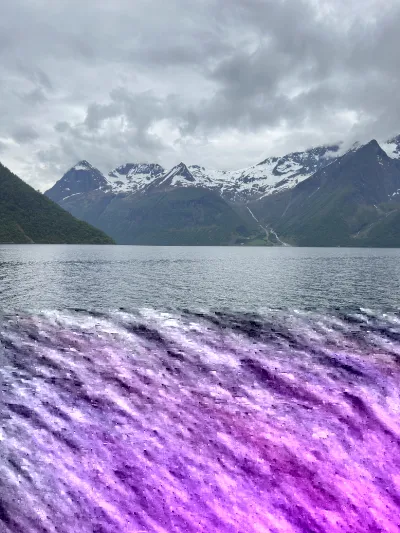 Panoramic view of a deep Norwegian fjord with snow topped mountains in the background