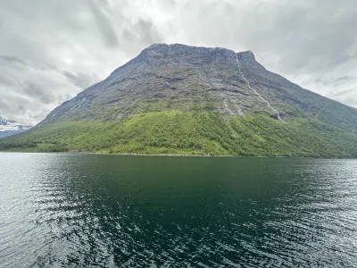 Lush green mountain slopes descending to the calm fjord waters below