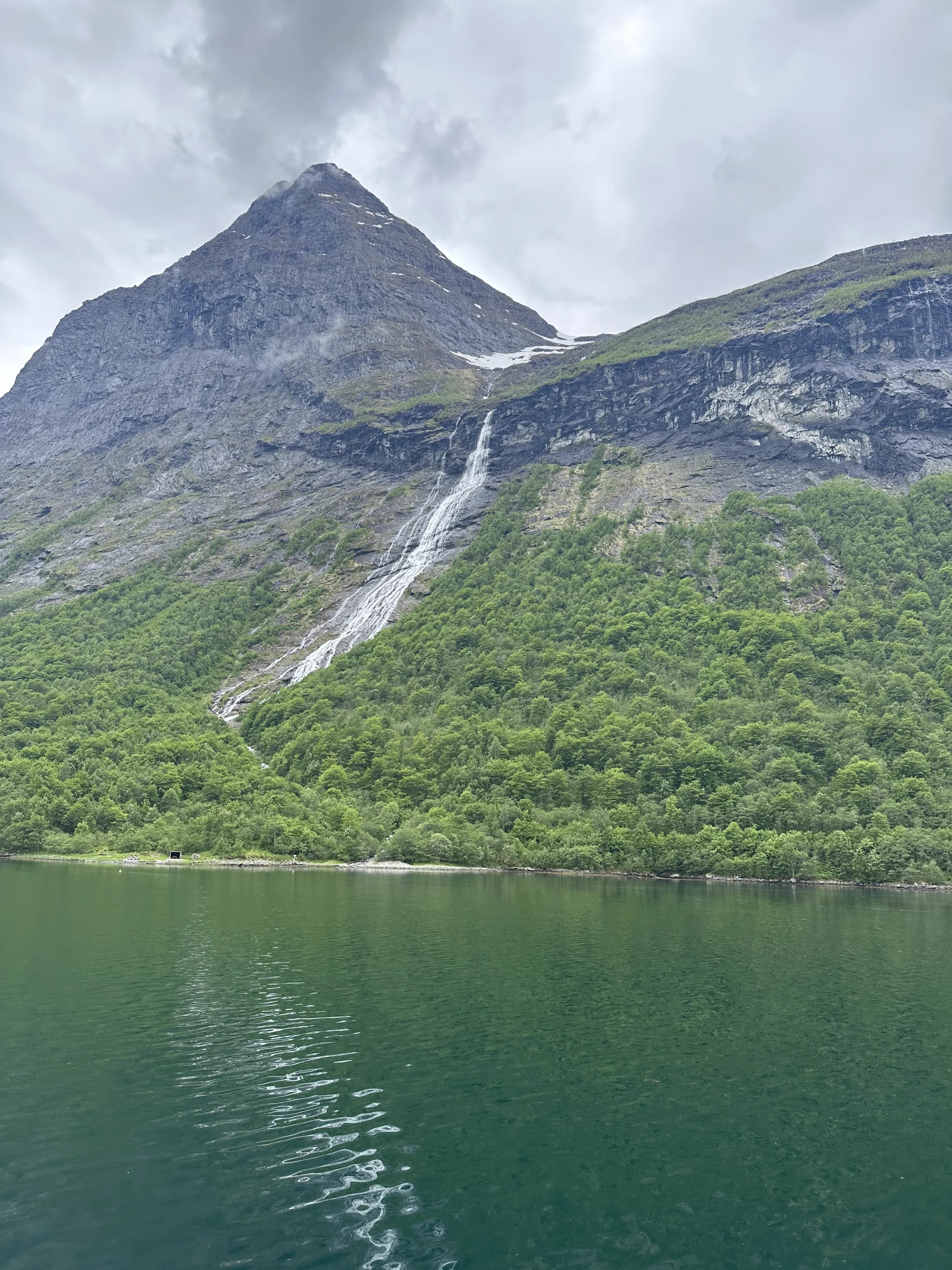 A waterfall cascading down the fjord cliffs into the water below