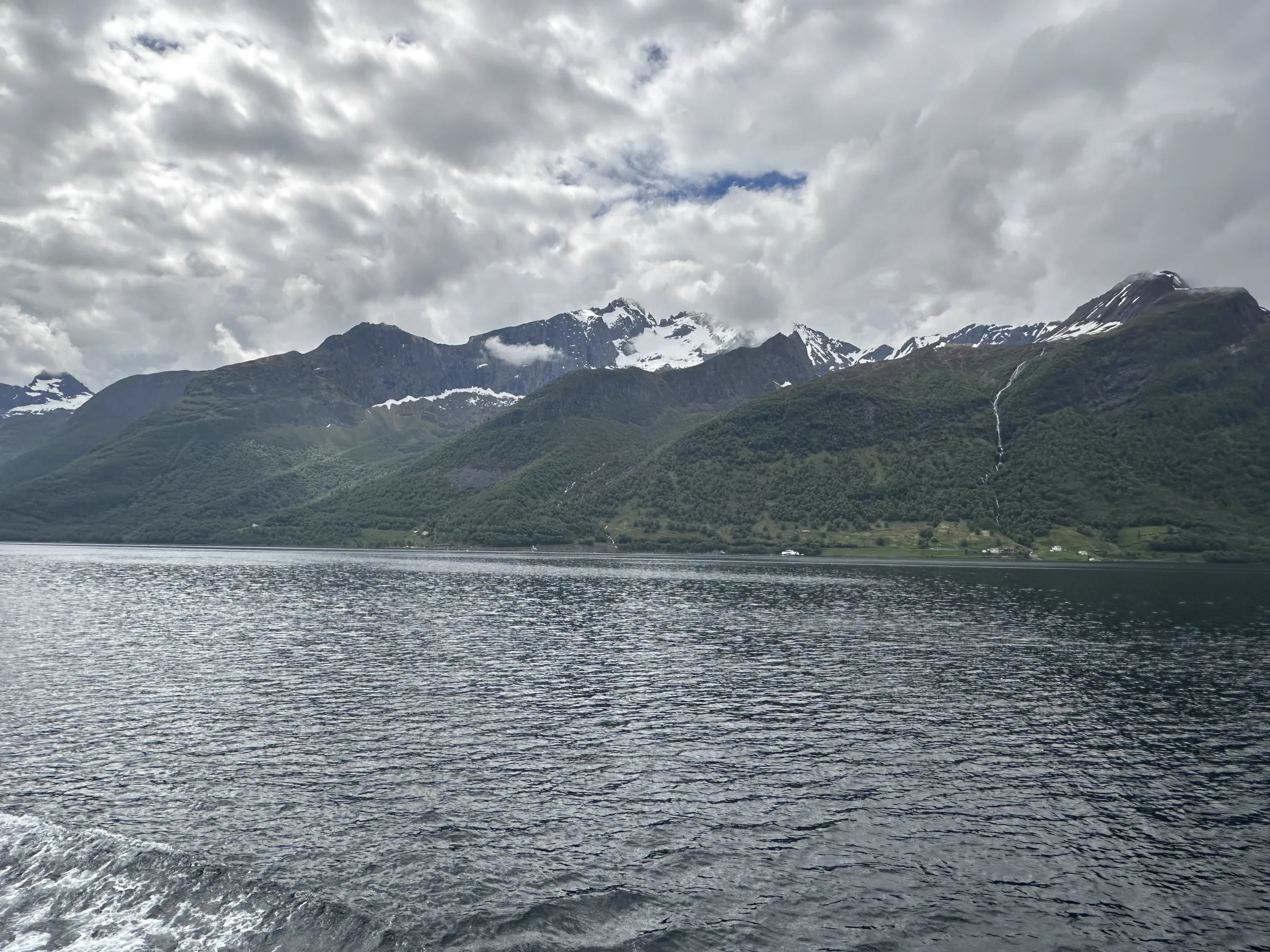 Fjord scenery during the cruise with snow topped mountains and houses littered throughout the scene