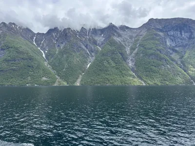 Ragged, steep cliff face with waterfalls running into the fjord